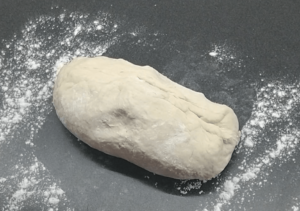 Dough on a countertop, sprinkled with flour.