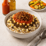 Egyptian koshari bowl served with hot sauce and garlic & vinegar sauce, and pickled vegetables