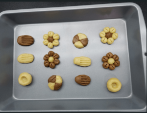 Piped betefour cookies ready for baking on a lined tray
