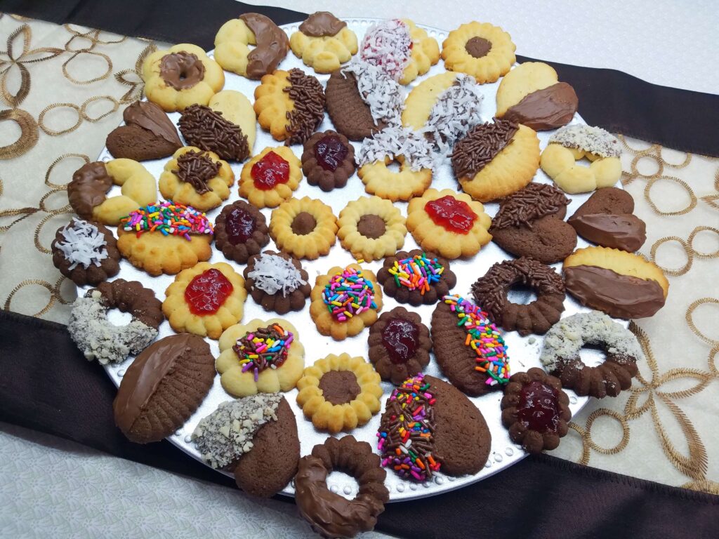 Egyptian Betefour cookies decorated with chocolate, jam, sprinkles, and coconut on a large platter.