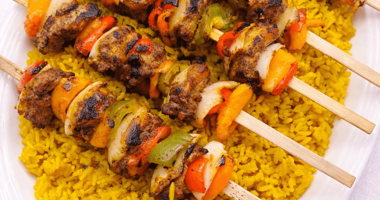 Middle Eastern Chicken Kebab skewers on a bed of yellow rice