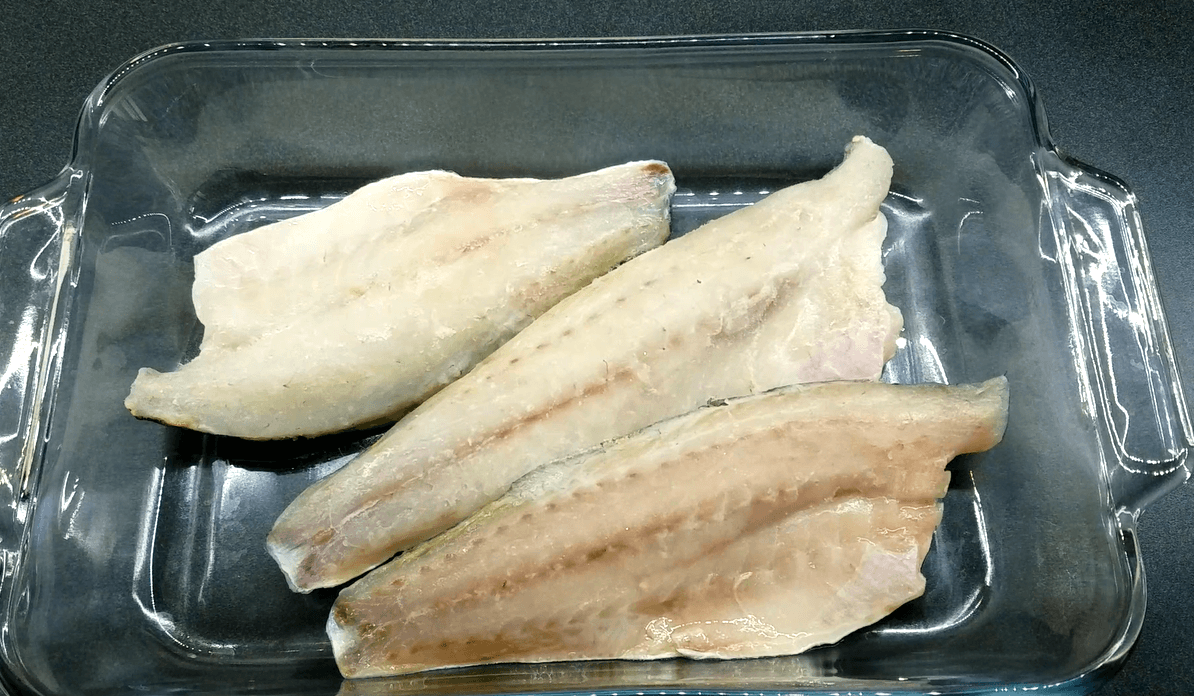 Seabass fillets arranged in a baking dish before seasoning