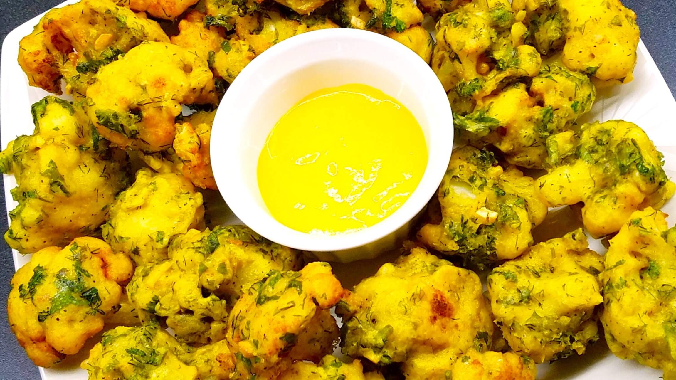 A close-up shot of crispy Egyptian fried cauliflower floret, showing the golden herb batter exterior.