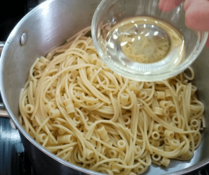 Adding oil to the pasta for the homemade koshari recipe
