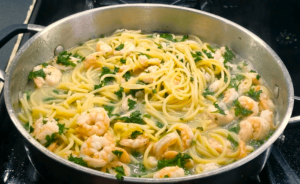 Tossing shrimp with pasta in garlic butter sauce for shrimp scampi