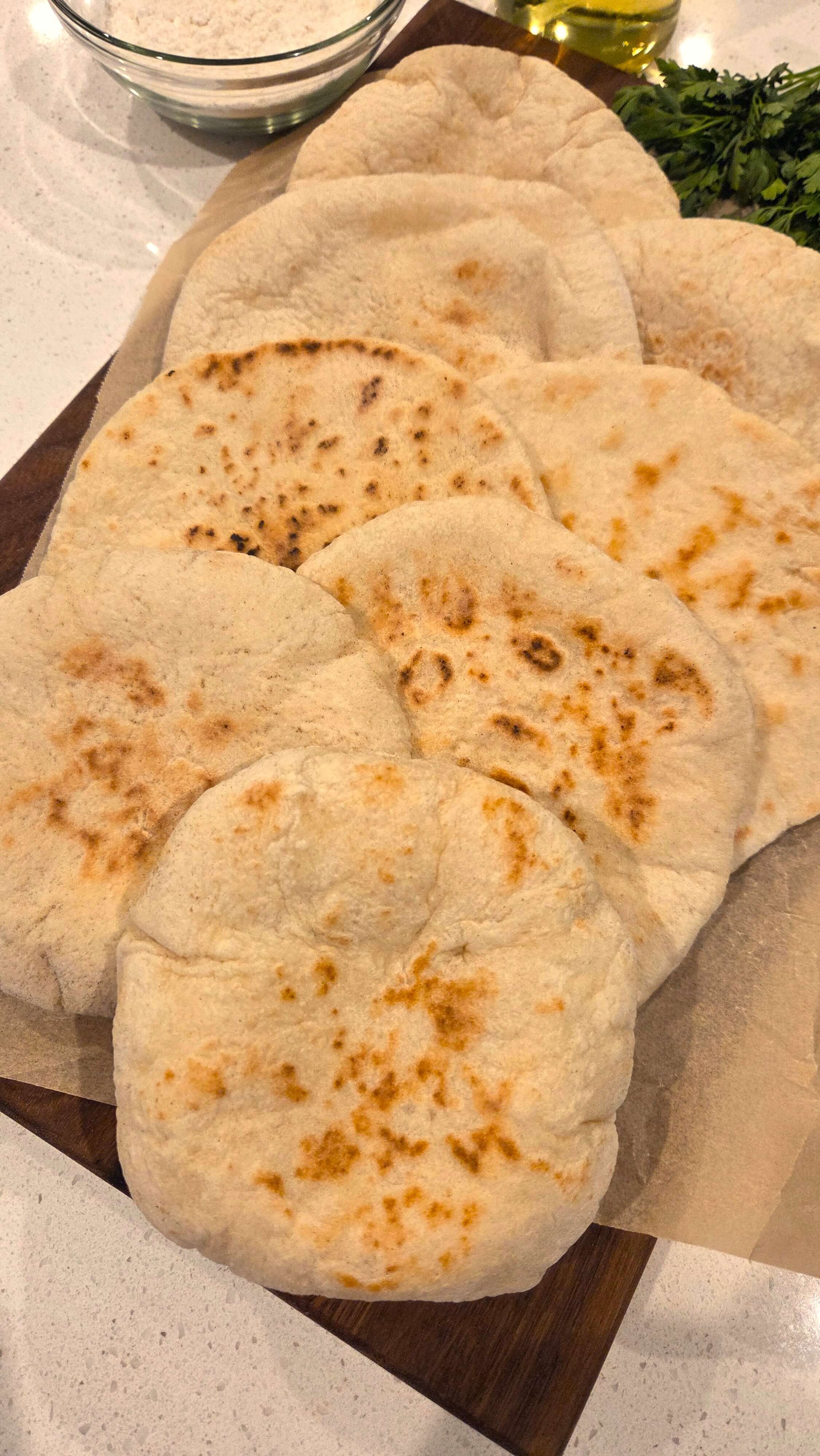 Pita bread stacked on a cutting board.