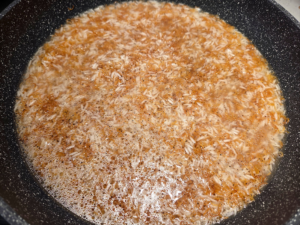 A pot of rice with vermicelli covered with water