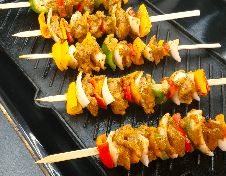 Middle Eastern chicken kebabs cooking on a hot grill until lightly charred and juicy.