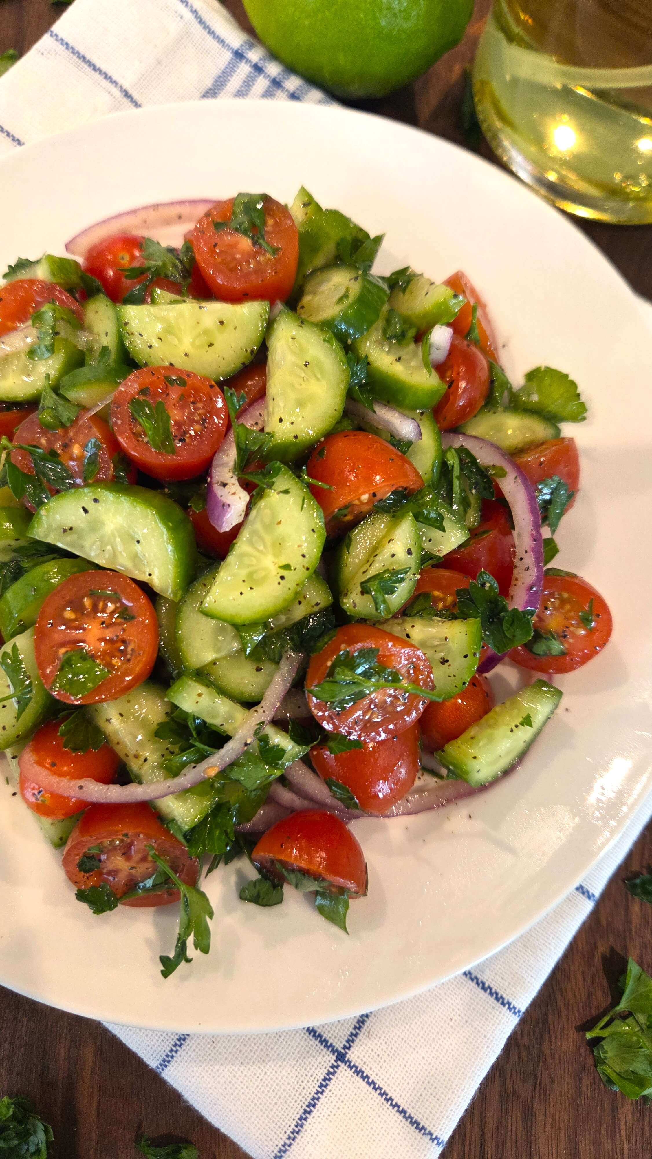 Overhead view of a healthy Mediterranean cucumber tomato salad served with fresh lemon.