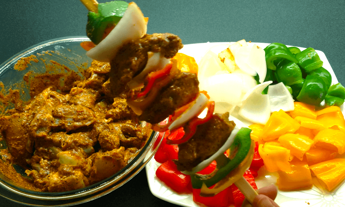 Marinated chicken, bell peppers, and onions threaded onto skewers before grilling