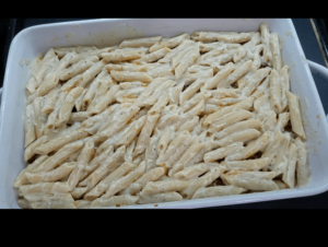 Baking dish layered with pasta with bechamel sauce and ground beef and topped with another layer of pasta with bechamel sauce