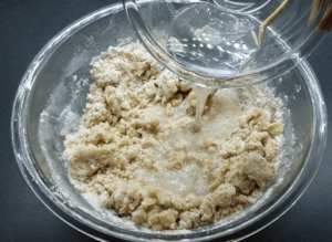 Pouring water into a bowl of flour