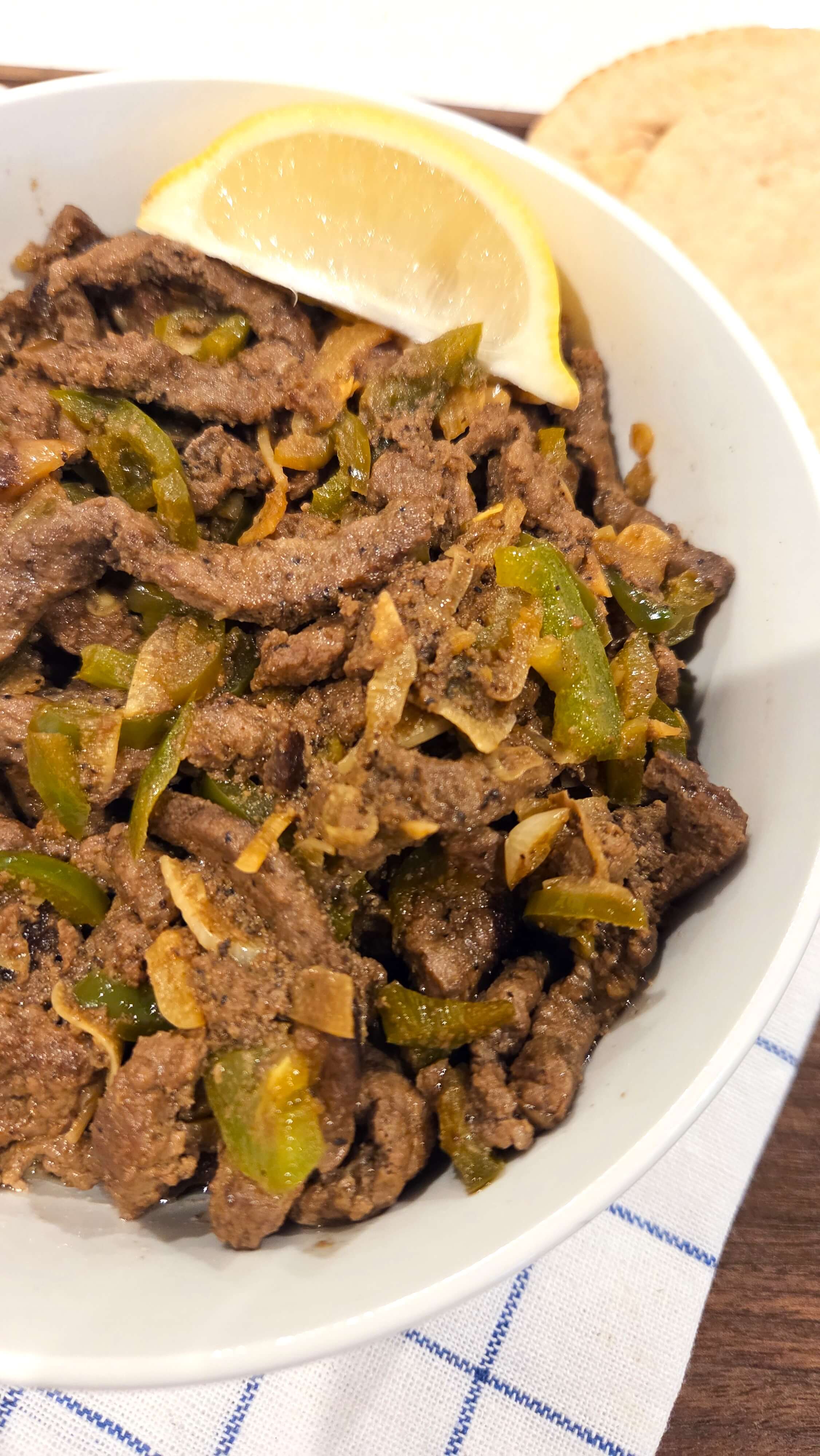 A premium close-up shot of a tender, juicy strip of authentic Kebda Eskandarani, showing the glossy, garlicky oil coating the meat.