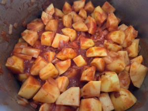 Adding chopped potatoes to tomato sauce for vegan Egyptian potato stew