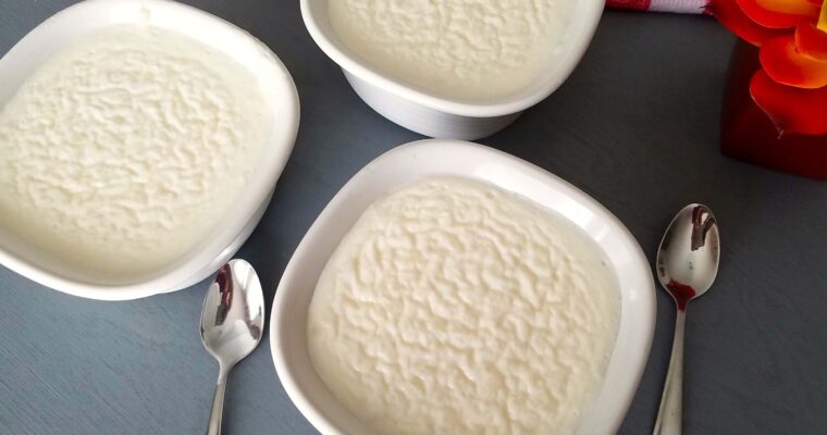 A wide overhead shot of multiple elegant dessert bowls filled with creamy Egyptian rice pudding.