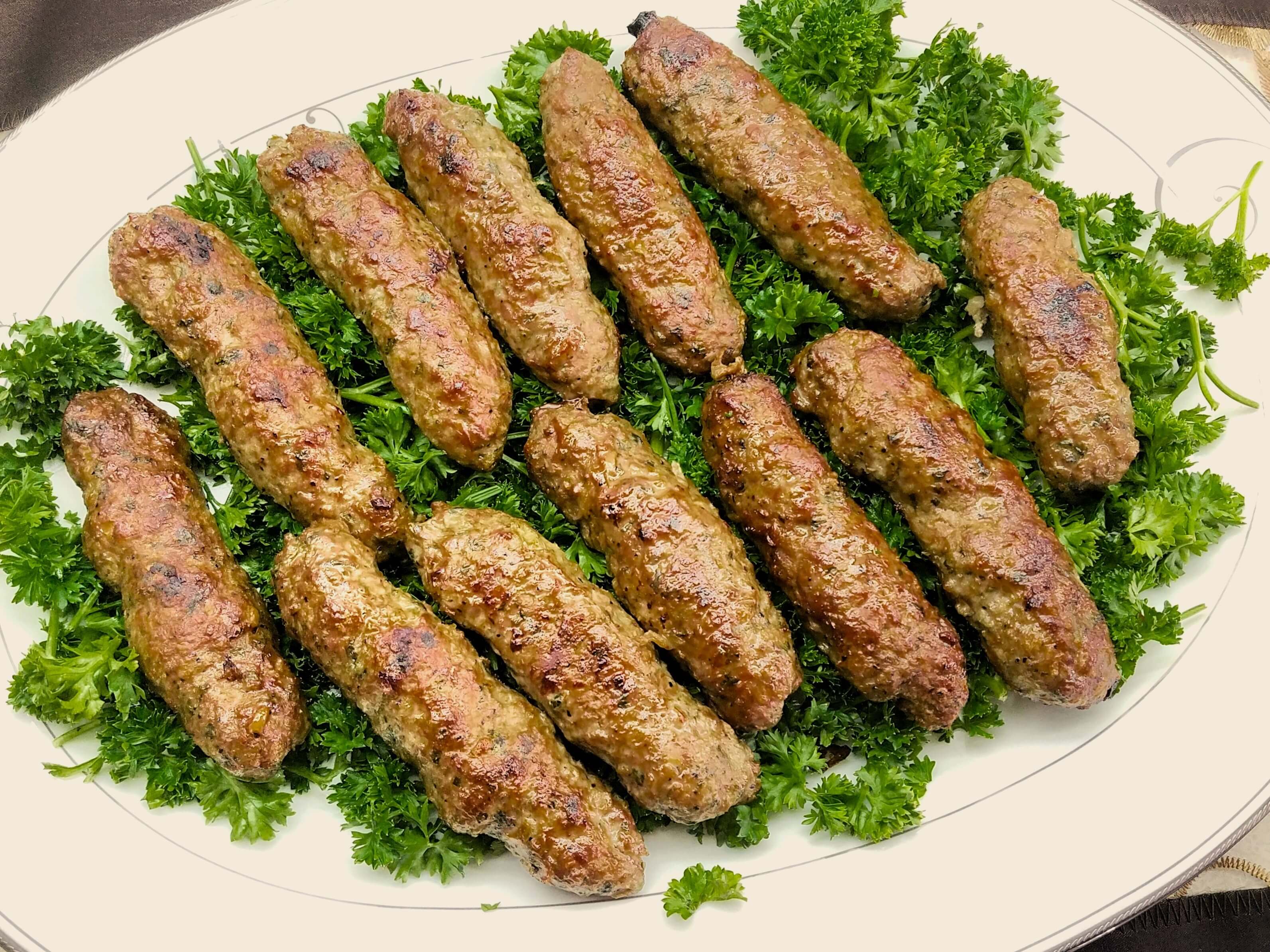 A premium close-up shot of Egyptian kofta kebab, highlighting the glistening, ultra-juicy exterior fat and flecks of fresh green parsley.