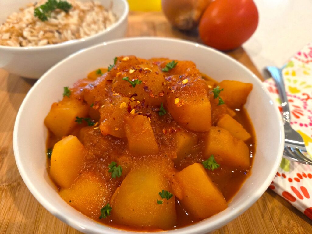 Vegan Egyptian potato stew with tender potatoes in a rich tomato base sauce with onions, topped with fresh herbs.