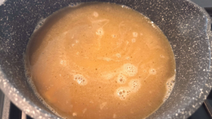 Chicken broth being added to toasted orzo pasta for Shorbet Lesan El Asfour soup