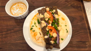 Assembling homemade doner kebab wrap with flatbread, salad, and tahini sauce