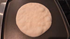 Cooking Turkish flatbread in a hot skillet until puffed