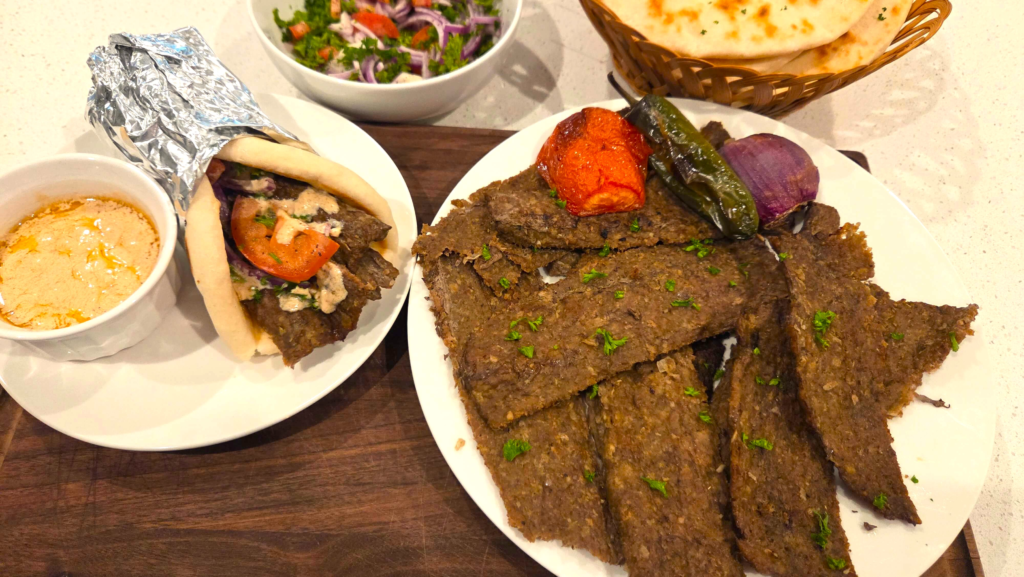 Turkish doner kebab wrap in flatbread with tahini sauce, onions, tomatoes, and parsley
