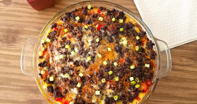 A wide overhead shot of a golden brown breakfast casserole with bread cubes and melted cheese in a baking dish.