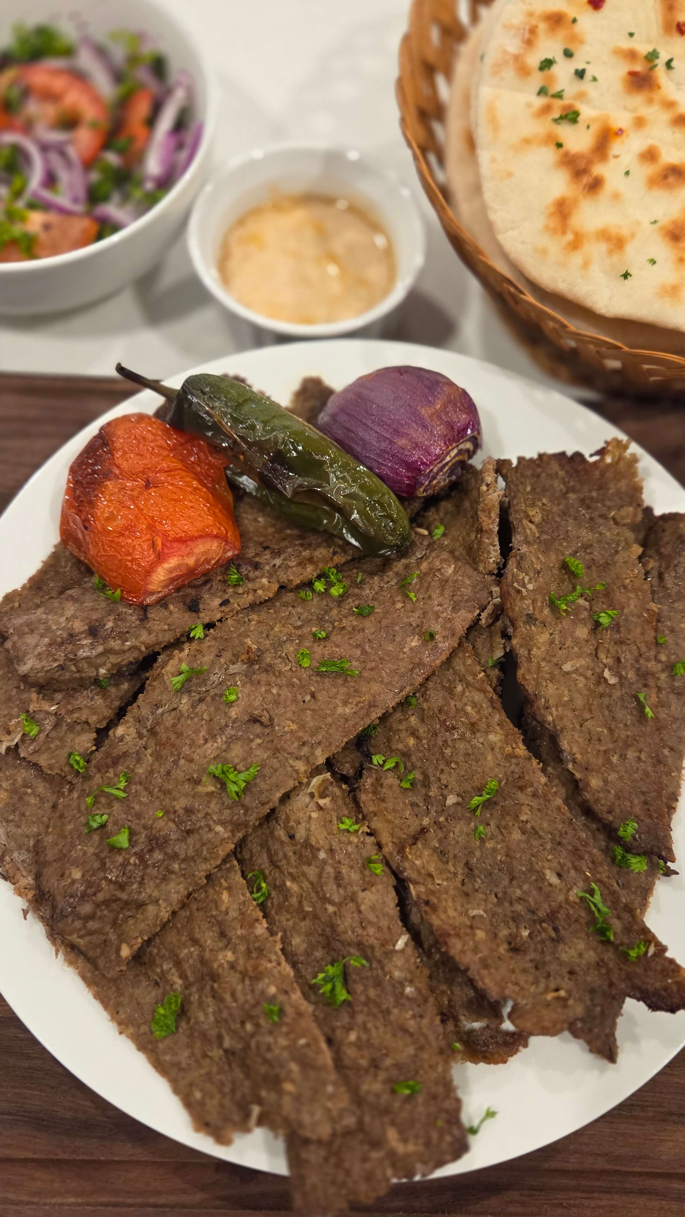 A premium close-up shot of paper-thin ribbons of seasoned ground beef kebab cooked in the oven, showing perfectly crispy, caramelized edges.