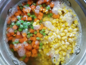 adding carrots peas and corn to chicken soup for flavor and texture
