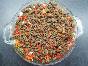 layering bread, cheese, peppers, and beef for Egyptian eggah