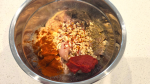 Marinade ingredients and spices added to raw chicken for honey garlic Mediterranean chicken
