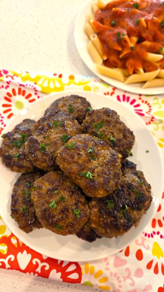 A beautiful top-down shot of juicy Turkish beef kofte patties served hot alongside warm pasta.