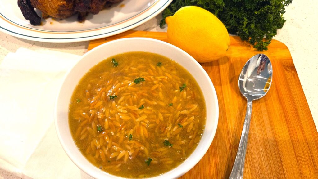 A beautiful close-up of a hot bowl of Shorbet Lesan El Asfour soup served alongside rotisserie chicken.