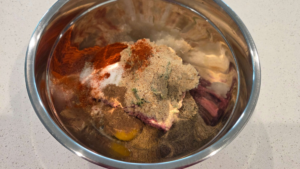 Ground beef, onion, breadcrumbs, egg, and spices in a bowl for Turkish beef kofte