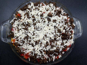 Sprinkling mozzarella cheese on top of the unbaked Egyptian eggah
