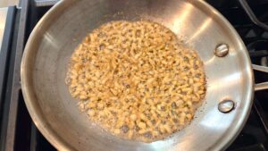 Ground coriander being stirred into garlic tasha for Egyptian molokhia
