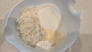 Adding dry ingredients to a bowl for vegan basbousa
