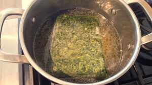 Frozen minced molokhia being added to chicken broth