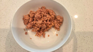 Drained canned tuna in a bowl for Mediterranean tuna salad.
