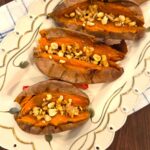 Easy baked sweet potato recipe with crispy skin served with honey, cinnamon, and chopped nuts