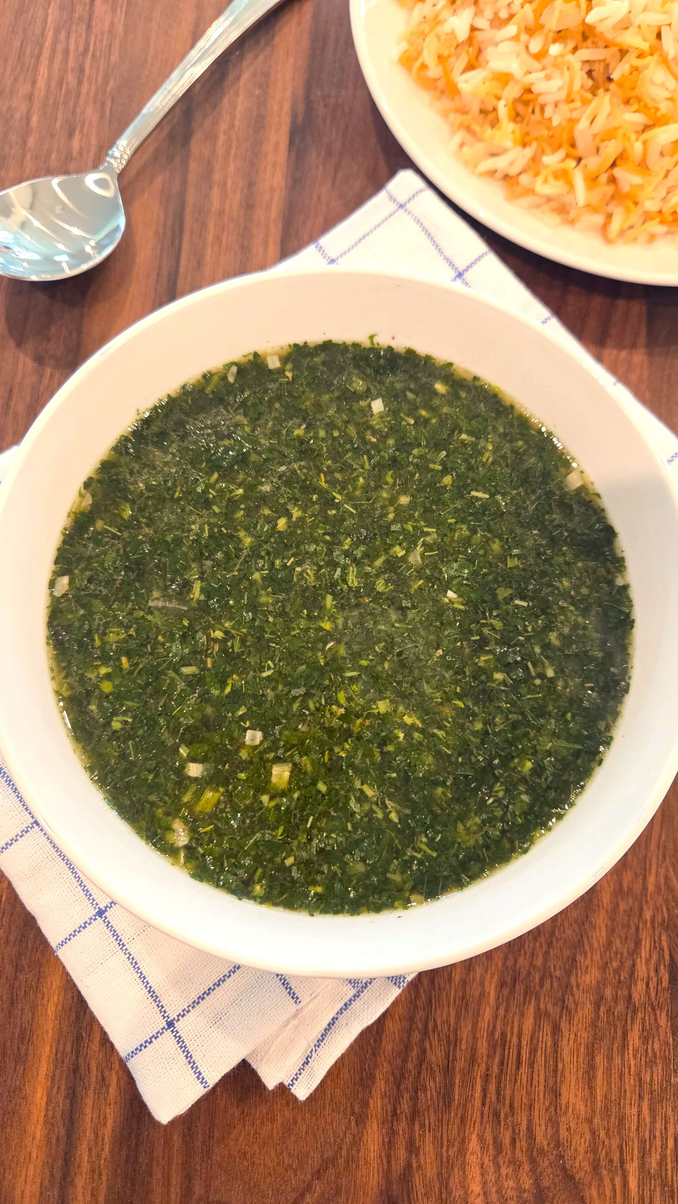 A close-up shot of a hot bowl of authentic Egyptian molokhia soup highlighting the sizzling garlic and coriander tasha on the surface.