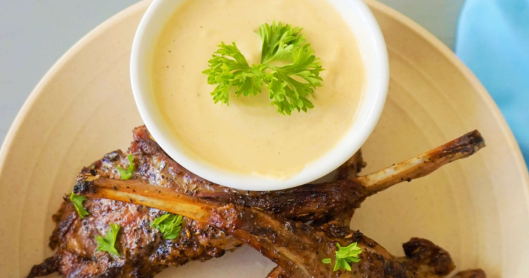 Mediterranean grilled lamb chops recipe served on a platter with fresh rosemary and parsley, served with tahini sauce