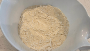 Semolina, coconut flakes, sugar, and baking powder mixed for vegan basbousa batter.