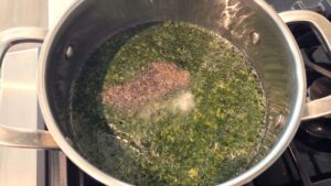 Molokhia simmering in broth with salt and black pepper