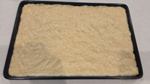 Vegan basbousa batter is spread evenly in a baking dish before baking.