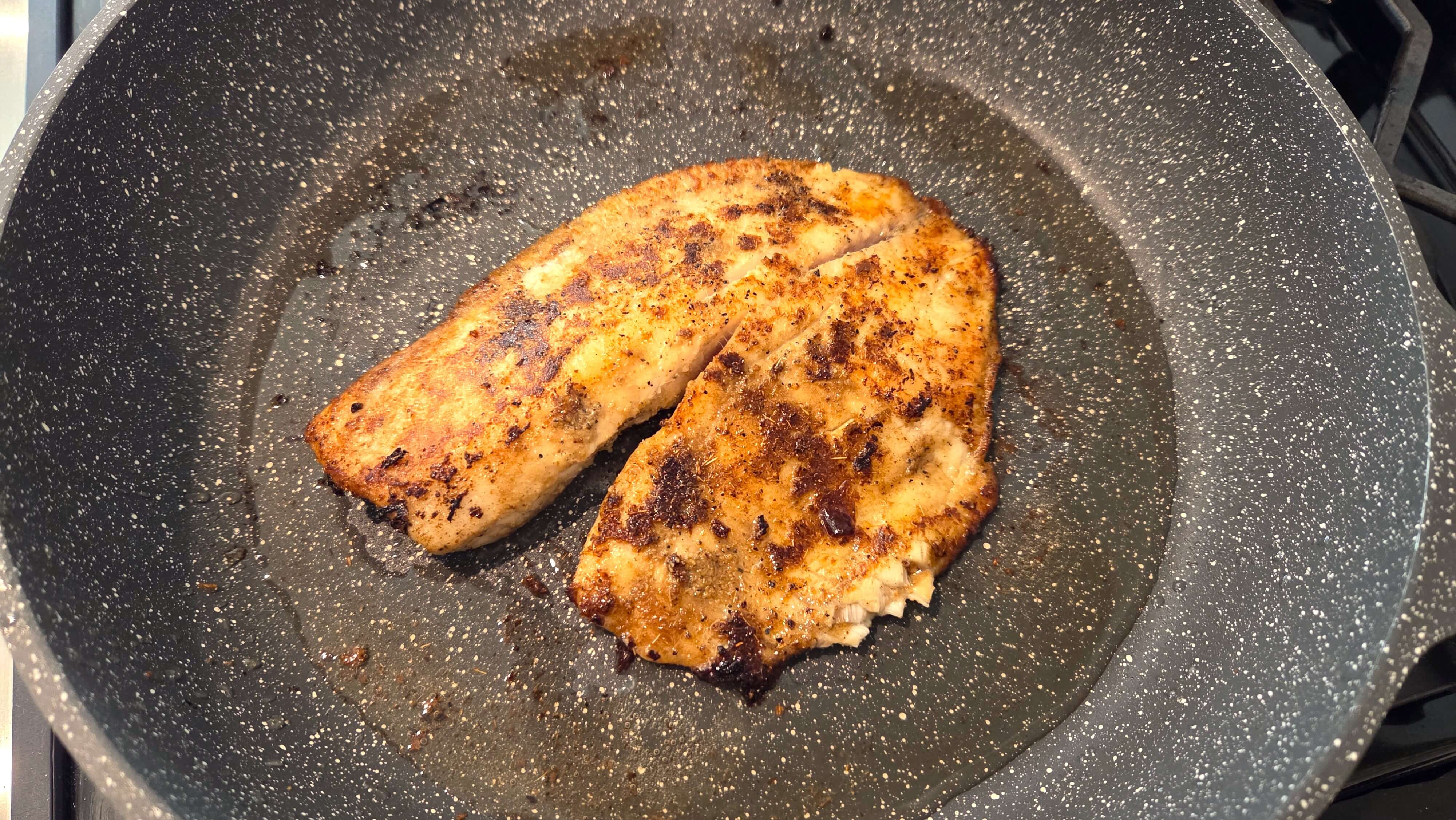 Pan seared tilapia fillets flipped to cook the second side until flaky and golden.