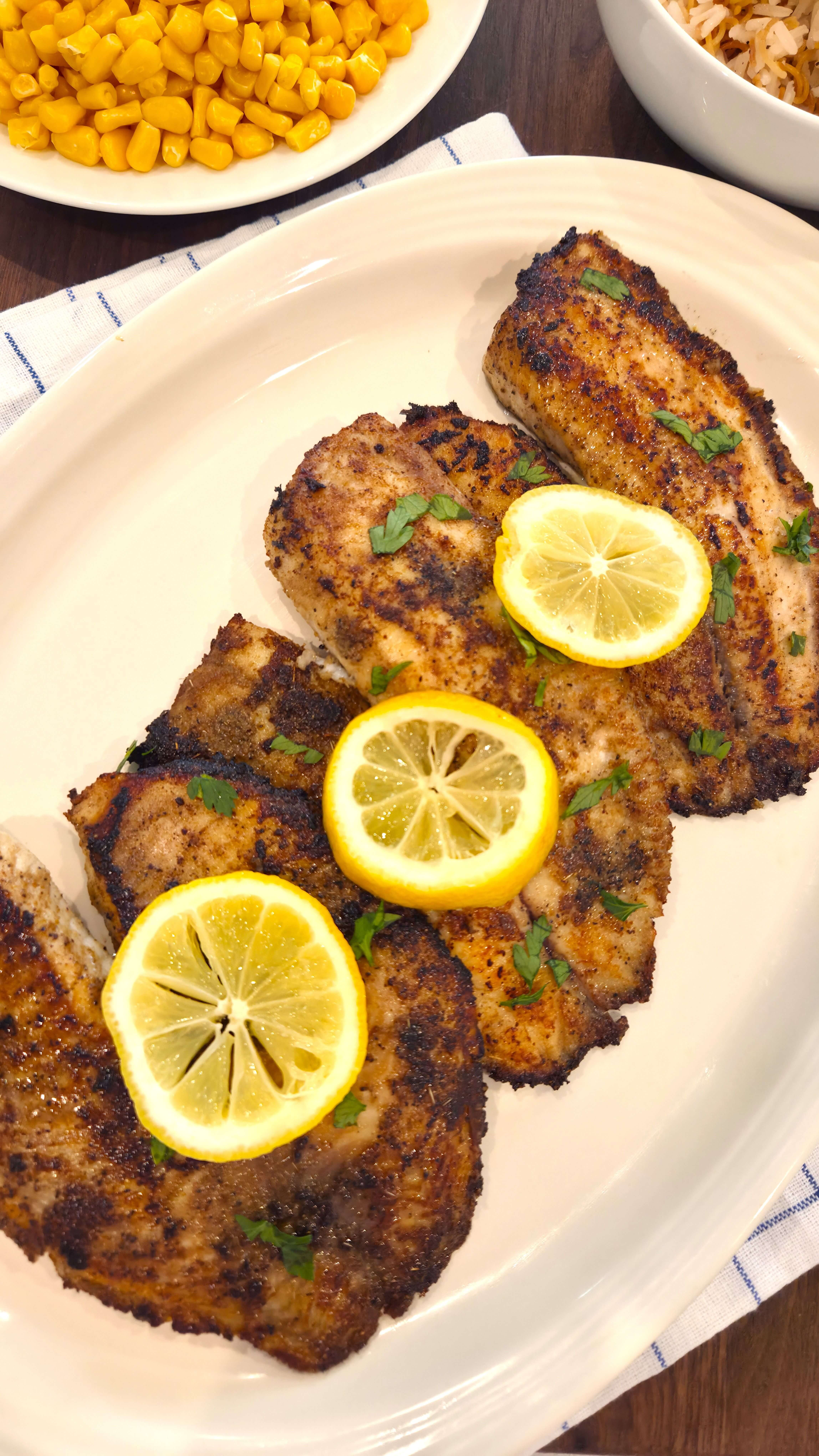 Mediterranean pan seared tilapia recipe served with lemon slices and fresh parsley.