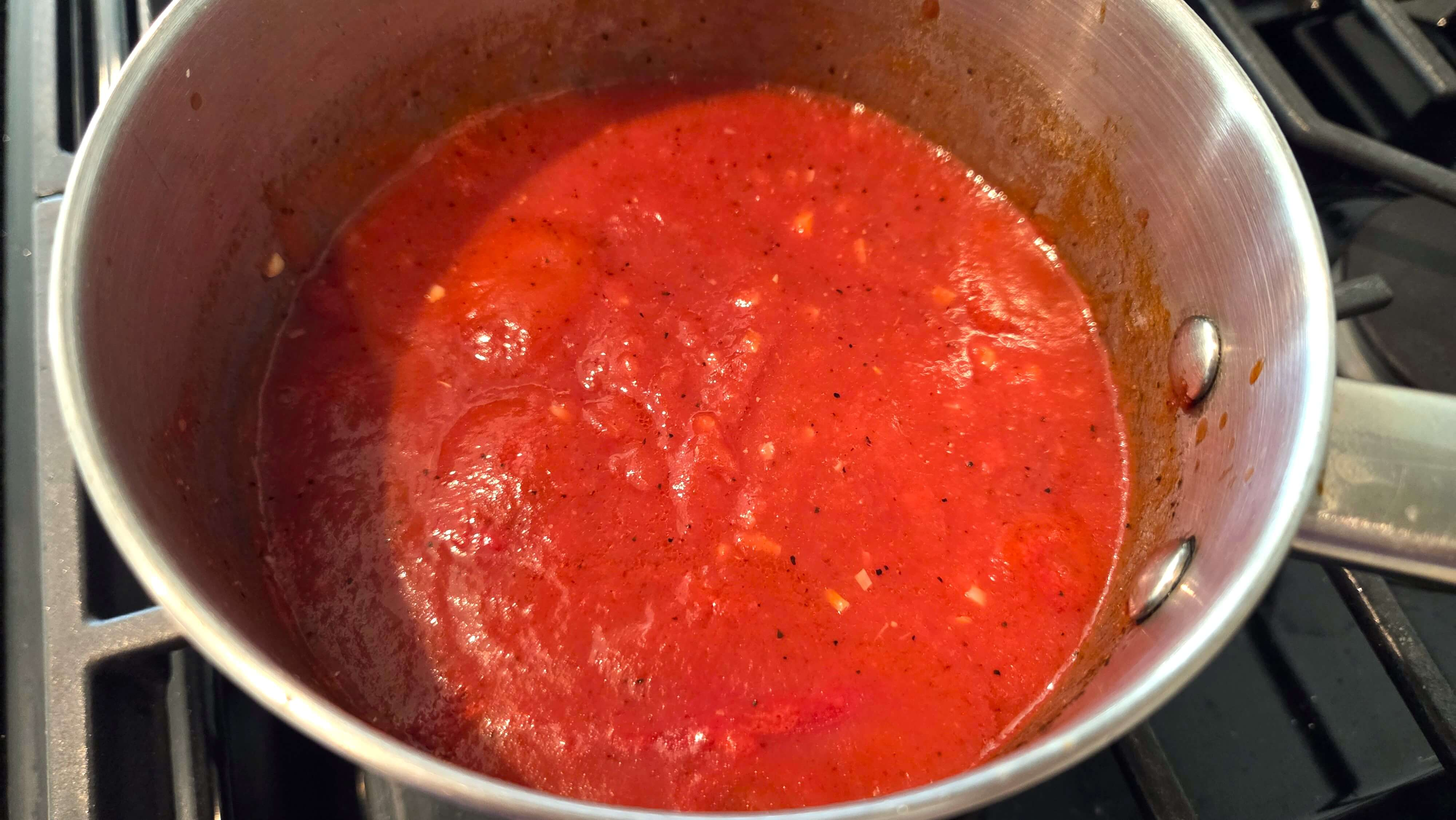 Tomato sauce simmering with garlic, white vinegar, cumin, and coriander.