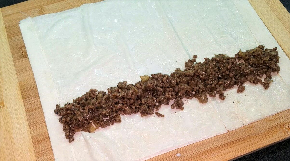 Seasoned ground beef filling placed along the edge of phyllo sheet