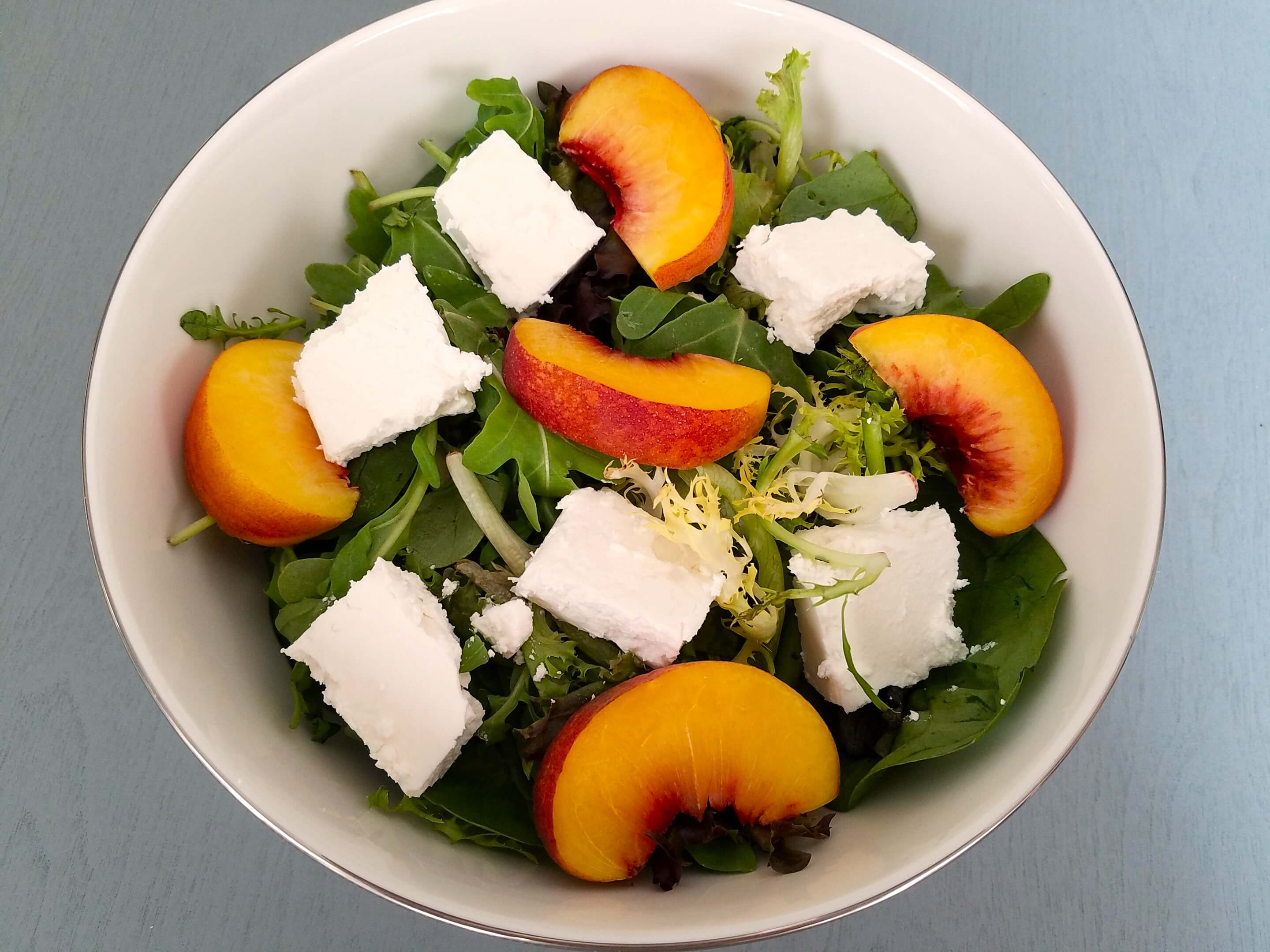 Sliced ripe peaches and cubed feta added to the mixed greens.