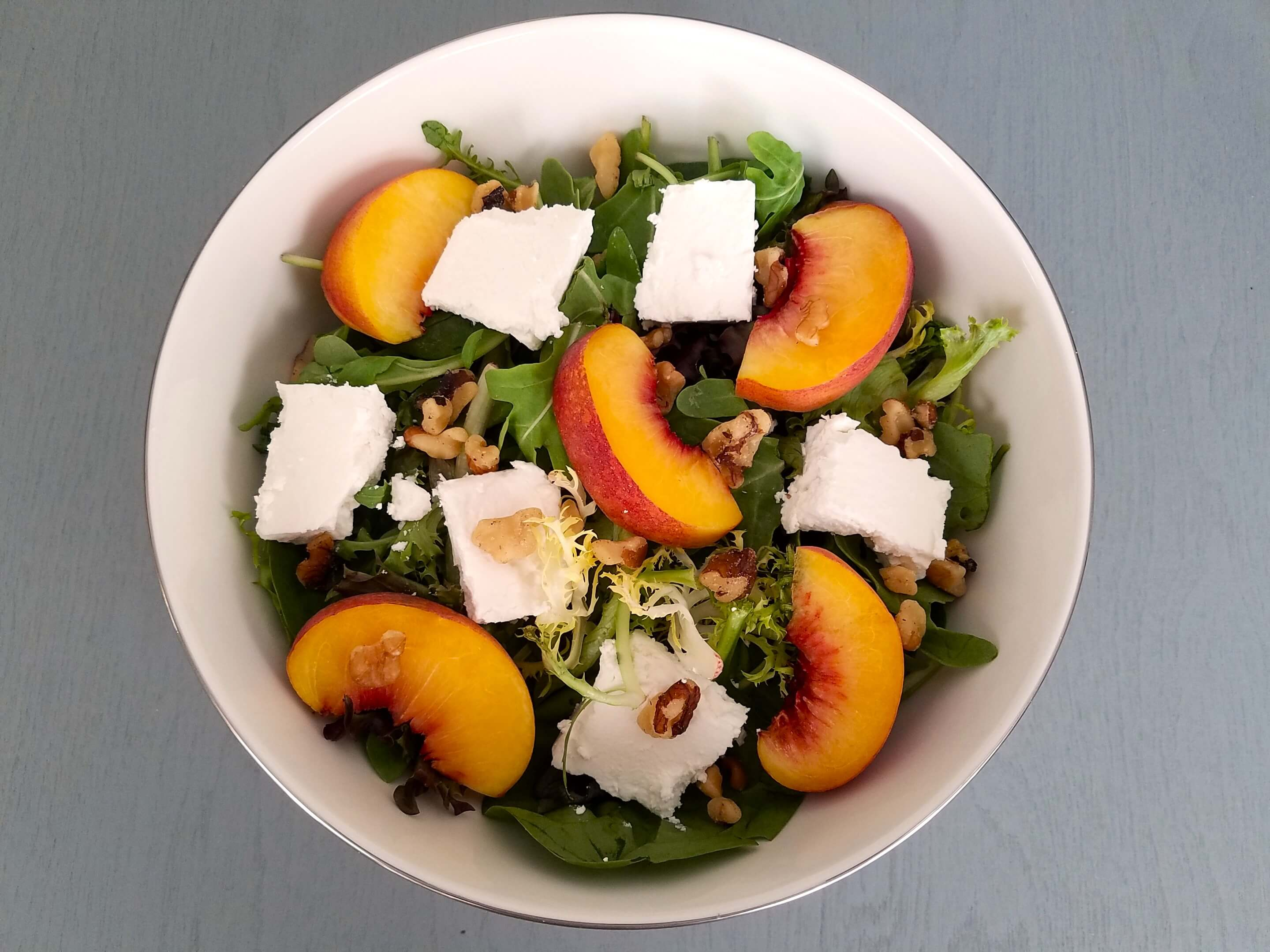 Chopped walnuts sprinkled over peaches, feta, arugula, and mixed greens.